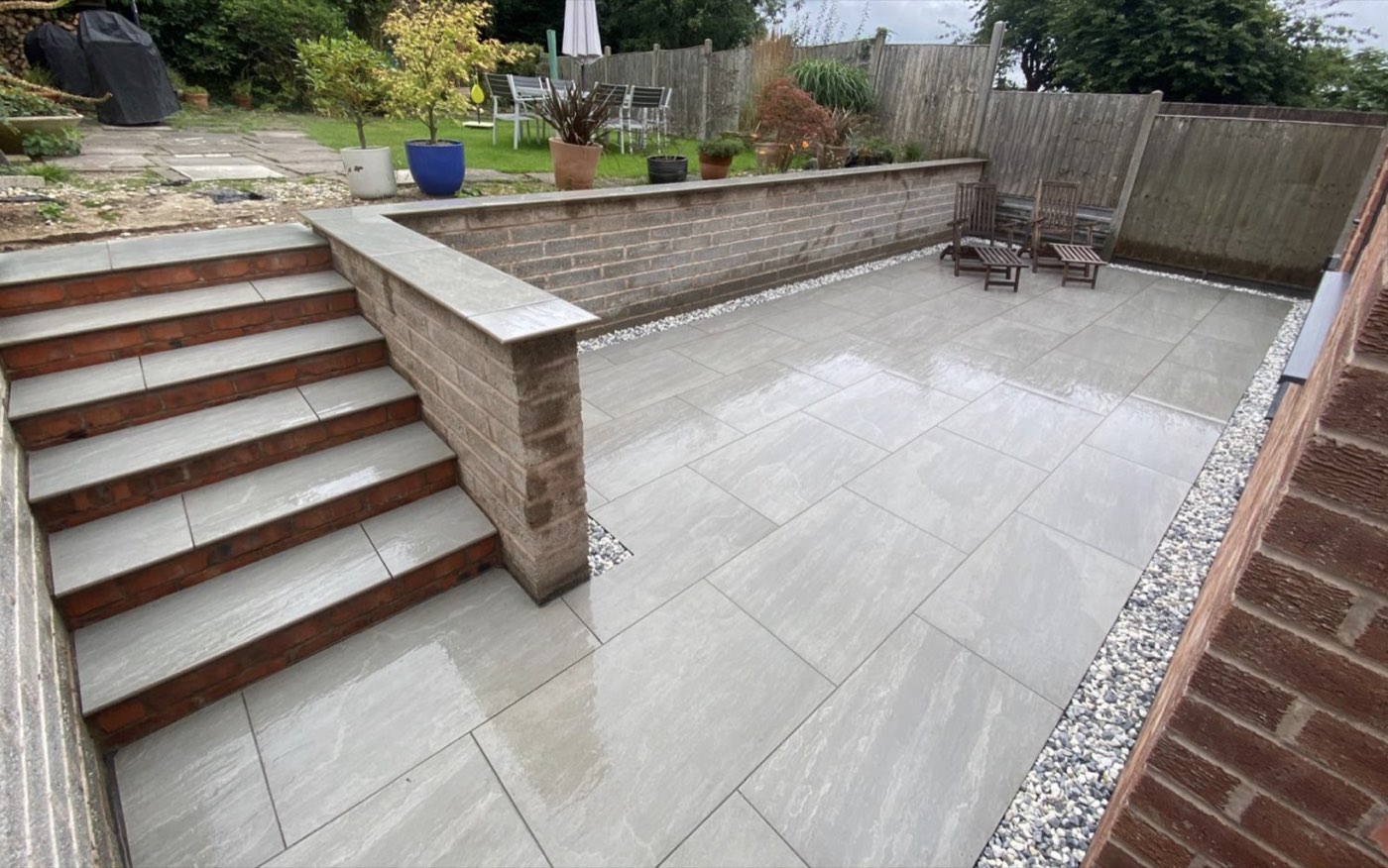 Finished porcelain patio with sleeper steps and retaining wall
